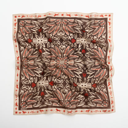 A square silk scarf with an intricate botanical and floral pattern, laid flat on a white background. The design features a dark brown center with cream-colored leafy motifs and small red floral accents, bordered by a cream edge with a red pattern.