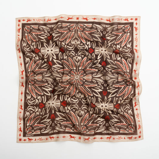 A square silk scarf with an intricate botanical and floral pattern, laid flat on a white background. The design features a dark brown center with cream-colored leafy motifs and small red floral accents, bordered by a cream edge with a red pattern.