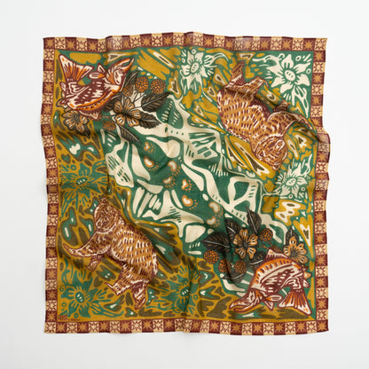 A square silk scarf featuring a detailed, vintage-style illustration of a tiger, fish, butterflies, and floral motifs in green, mustard yellow, brown, and cream, finished with a patterned border.