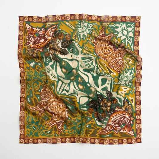 A square silk scarf featuring a detailed, vintage-style illustration of a tiger, fish, butterflies, and floral motifs in green, mustard yellow, brown, and cream, finished with a patterned border.