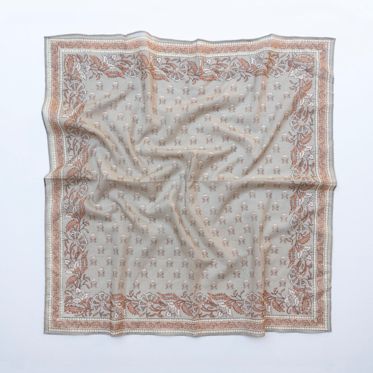 A square silk scarf with an intricate pattern of small monogram motifs and a floral border, laid flat on a white background.