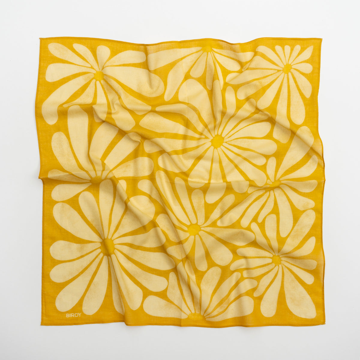 A square scarf with a bold yellow and cream floral pattern, laid flat on a light gray background. The brand name 'BIRDY' is printed in small letters in the bottom-left corner.