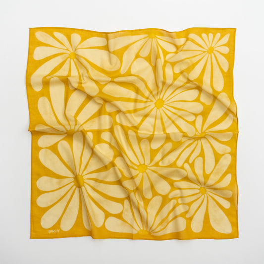A square scarf with a bold yellow and cream floral pattern, laid flat on a light gray background. The brand name 'BIRDY' is printed in small letters in the bottom-left corner.