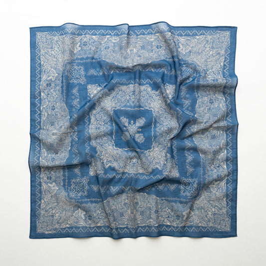 A square blue patterned scarf with a white floral and geometric print, laid flat on a white background.
